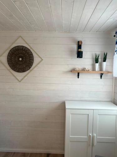 a kitchen with white walls and a shelf with plants at Domek Chabrowy Gowidlino in Gowidlino