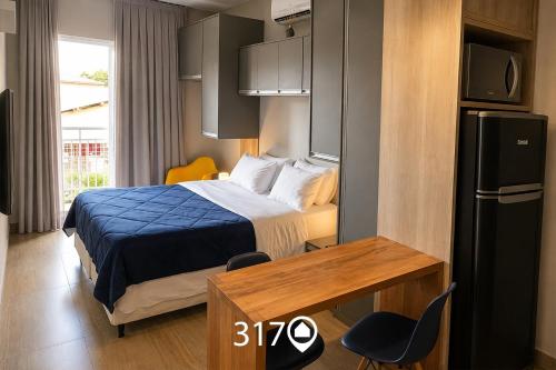 a bedroom with a bed and a desk and a refrigerator at Studio com Garagem e Acessibilidade | Granja Viana in Taboão da Serra