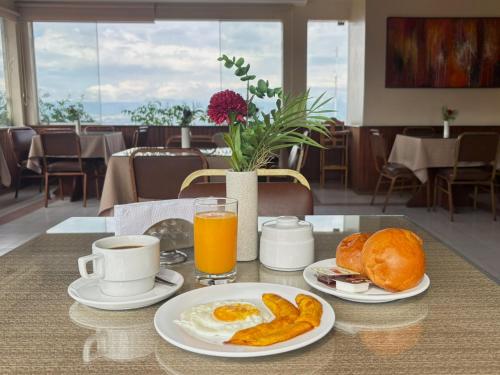 Ein Tisch mit zwei Tellern Frühstücksspeisen und Orangensaft in der Unterkunft Hotel Monte Azul in Tarapoto