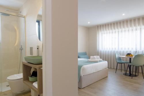 a bedroom with a bed and a bathroom with a sink at Calvário Suites III in Chaves
