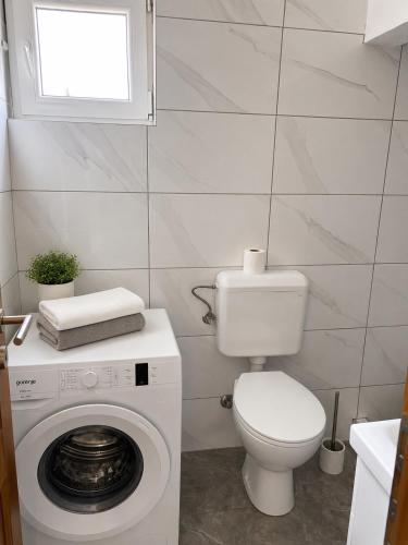 a bathroom with a toilet and a washing machine at Harmony apartment in Foča