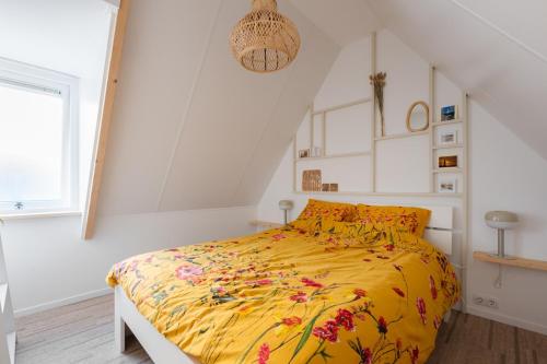 a bedroom with a bed with a yellow comforter at Kortbie Zee in Biggekerke