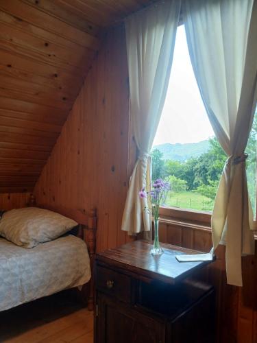 a bedroom with a bed and a vase of flowers on a table at Vikendica ZORA in Foča