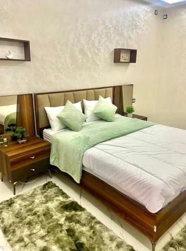 a bedroom with a large bed with green sheets and pillows at Fes Golf Residence in Fez