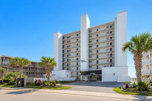 a large white building with palm trees in front at Ocean Towers Resort in Myrtle Beach