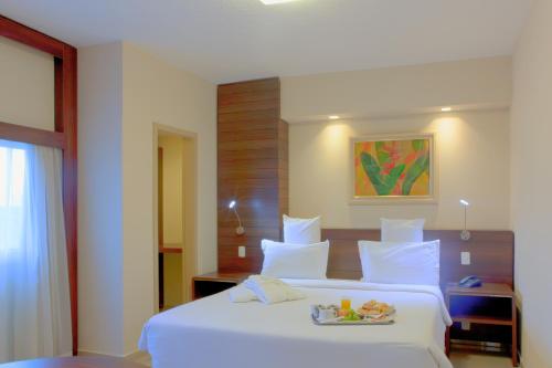 una camera da letto con un letto bianco e un vassoio di cibo sopra di Royal Center Hotel Lourdes a Belo Horizonte
