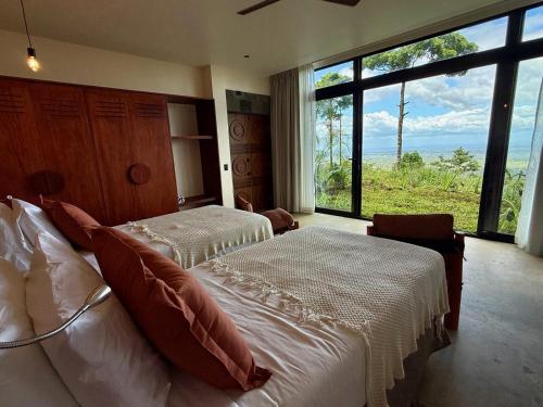 a bedroom with two beds and a large window at Origins Astral in Bagaces