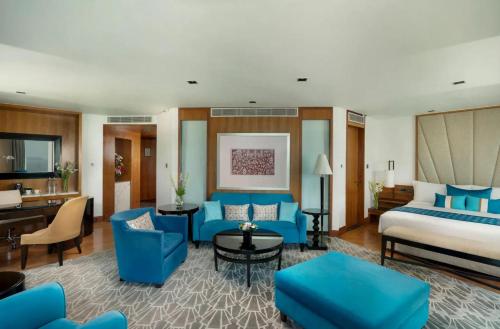 a hotel room with a king sized bed and blue furniture at Hotel DSR Krone New Delhi in New Delhi