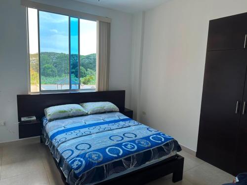 a bedroom with a bed and a large window at Departamento impecable en Tonsupa, Conjunto Vacacional Salaverry VI in Tonsupa
