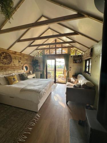 a bedroom with a large bed and a couch at Pinetree Lodge, Cotswolds in Mickleton