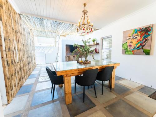 a dining room with a wooden table and chairs at Luxe Pearl in Paternoster