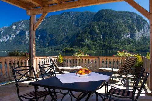 a table and chairs on a deck with a view of a mountain at Seehotel Grüner Baum in Hallstatt