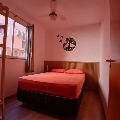 a bedroom with a bed with red sheets and a clock at Apartamento Aconchegante! in Uberaba