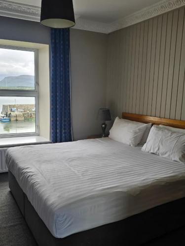 a bedroom with a large bed with a window at The Beach Hotel in Mullaghmore