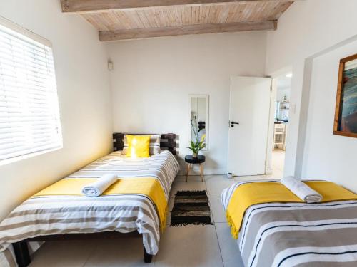 two beds in a room with white walls at Ivory Pearl in Paternoster