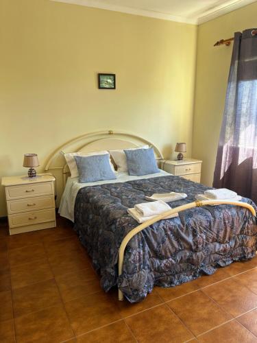 a bedroom with a large bed with blue pillows at Propriedade dos Seixos in Moledo
