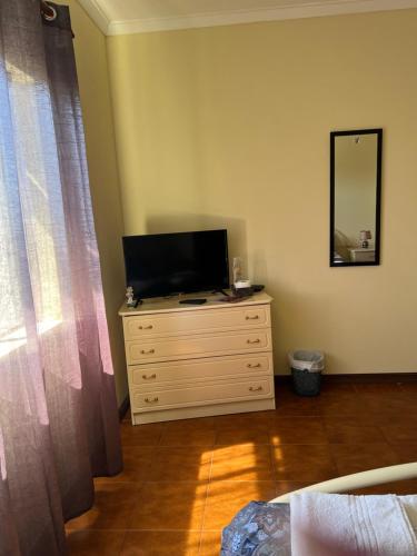 a bedroom with a television on a dresser with a mirror at Propriedade dos Seixos in Moledo