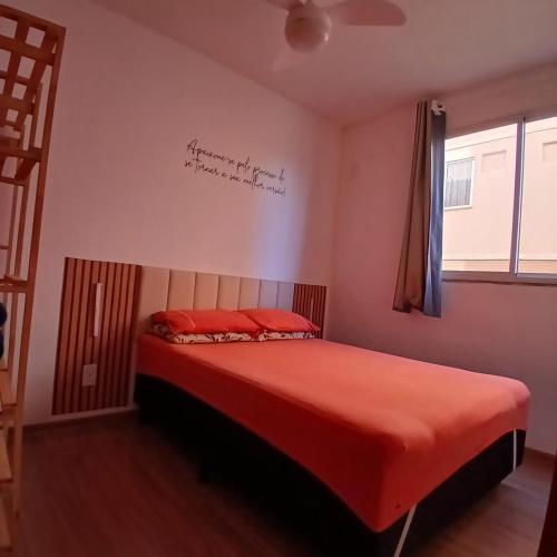 a bedroom with a bed with red sheets and a sign on the wall at Apartamento Sossego! in Uberaba