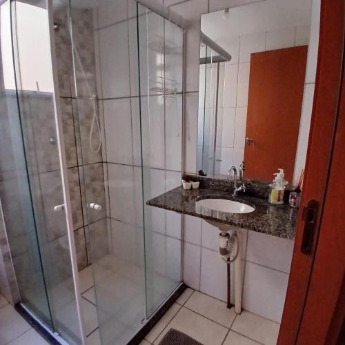 a bathroom with a glass shower and a sink at Apartamento Sossego! in Uberaba