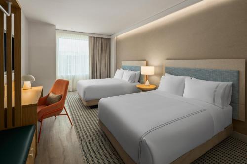 a hotel room with two beds and a chair at EVEN Hotel Orlando Universal Blvd by IHG in Orlando