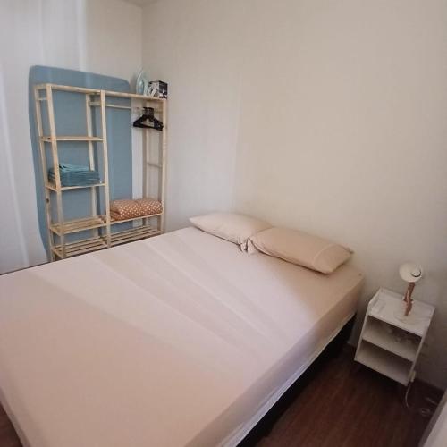 a white bed in a room with a shelf at Apartamento Serenidade! in Uberaba
