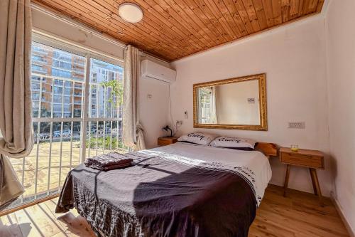 a bedroom with a bed and a large window at Bright 2 Bedroom, Private Garden in Herzliya