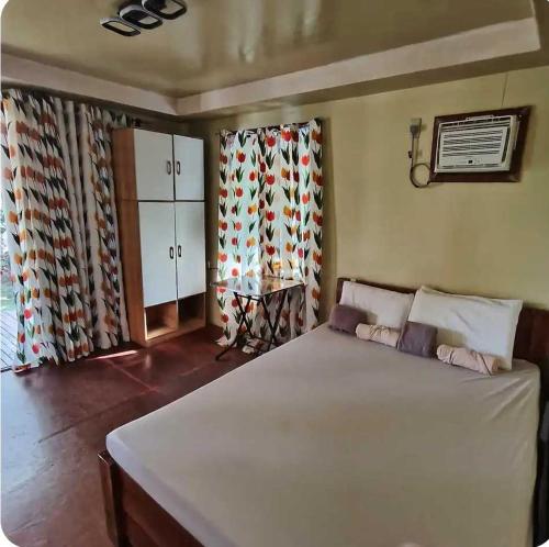 a bedroom with a large white bed and curtains at CocoVille Guesthouse KUBO in Alegria