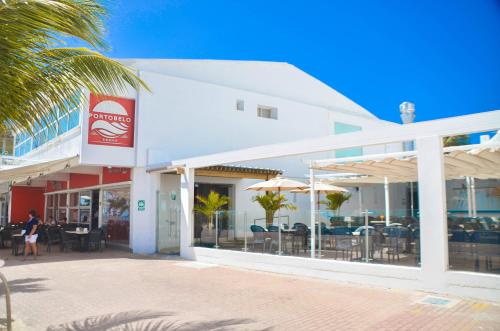 ein weißes Gebäude mit Tischen, Stühlen und Sonnenschirmen in der Unterkunft Hotel Portobelo beach in San Andrés