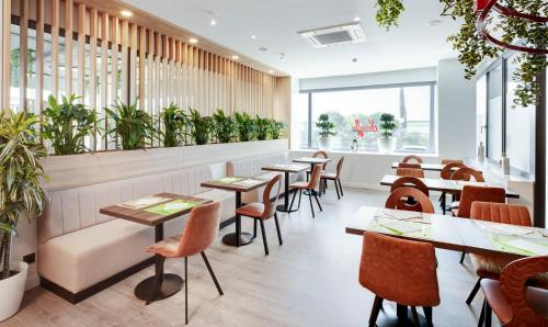 a restaurant with tables and chairs and plants at Sercotel AB Rivas in Rivas-Vaciamadrid