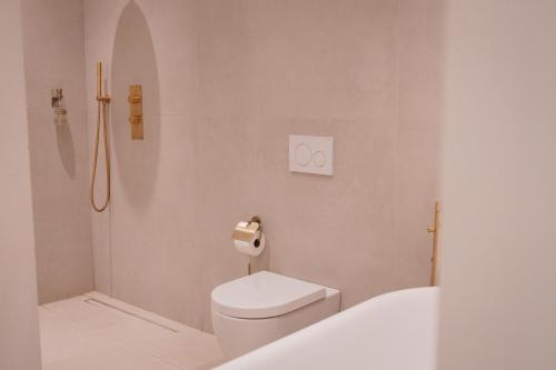 a white bathroom with a toilet and a shower at Onder de Linde B&B in Valkenburg