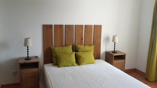 1 dormitorio con 1 cama con almohadas amarillas y 2 lámparas en Praia Verde Residence, en Praia Verde