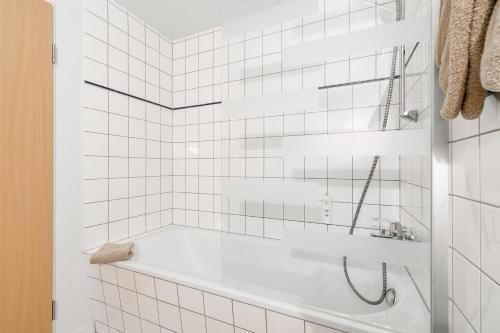 a white tiled bathroom with a bath tub at Hotel Am Bühl in Eibenstock