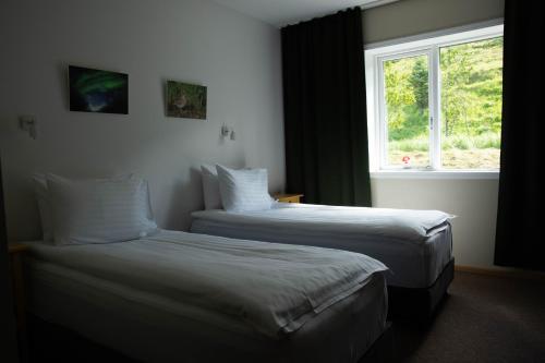 two beds in a hotel room with a window at Hótel Búrfell in Vík