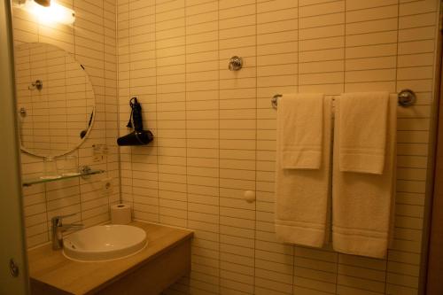 a bathroom with a sink and a mirror and towels at Hótel Búrfell in Vík