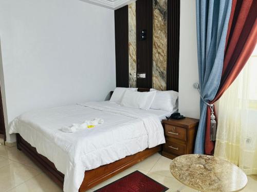a bedroom with a bed with white sheets and a table at Hotel Mandelson in Godomey