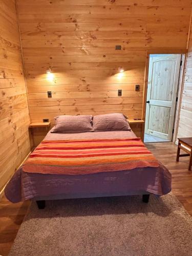 a bedroom with a bed in a wooden room at Cabañas en neltume in Neltume