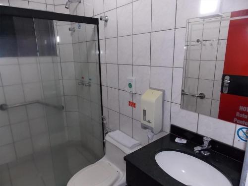 a bathroom with a shower and a toilet and a sink at Hotel Rota do Pantanal in Presidente Prudente