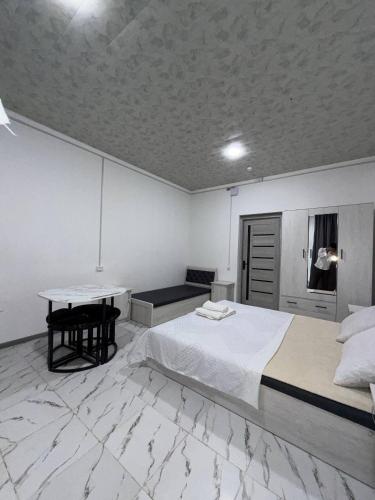 a white bedroom with a bed and a table at 888 отель in Yunusobod