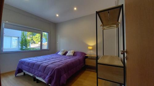 a bedroom with a purple bed and a window at Brisas Apart in Olavarría
