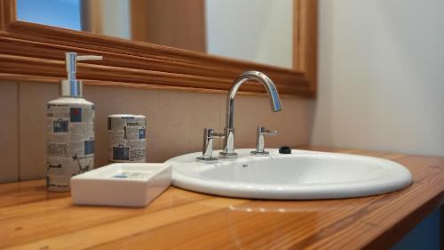 a white sink sitting on a wooden counter in a bathroom at Brisas Apart in Olavarría