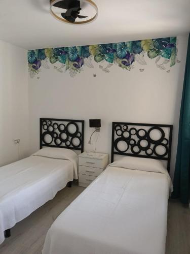 two beds in a room with white walls at Enjoy Morro Jable in Morro del Jable