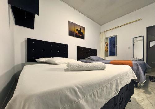 a bedroom with two beds with white sheets at Hotel Alcaraván Aguazul in Aguazul