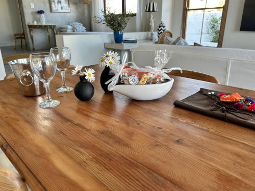 a wooden table with a bowl of food and wine glasses at Duneberry Beach Studio in Yzerfontein