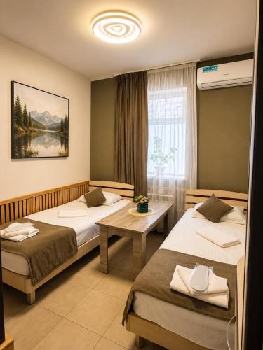 ein Hotelzimmer mit zwei Betten und einem Tisch in der Unterkunft MarNar Hotel in Yerevan
