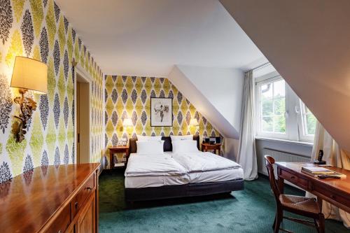 a bedroom with a bed and a desk and a window at Romantik Hotel Hof zur Linde in Münster