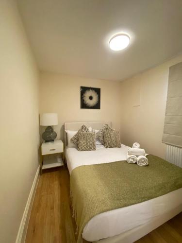 a bedroom with a large white bed with a green blanket at Riverside 2 Bedroom Apartment - Central Location in Kingston upon Thames