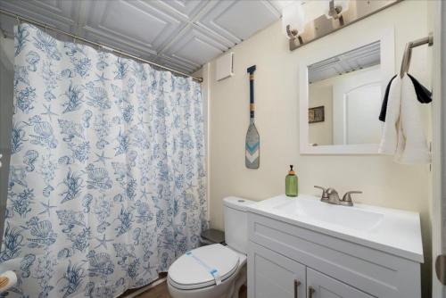 a bathroom with a sink and a toilet and a shower curtain at The Beachside Co in Sylvan Beach