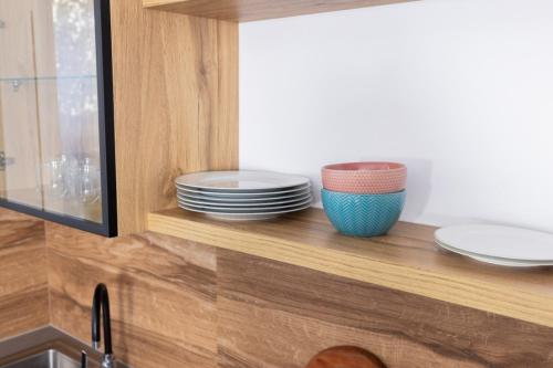 a kitchen with plates and bowls on a wooden shelf at Garden View Apartment in Rrushkull