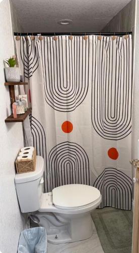 a bathroom with a toilet and a shower curtain at Small Space Charm in Tampa