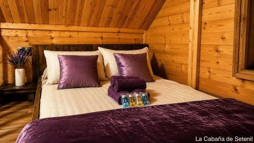 a bed in a wooden room with purple pillows at Villa Soñada Setenil in Setenil